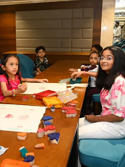 A young girl looks up from her painting, while others around her are busy creating. Our workshops are designed to hold children's attention and provide a space where they can explore art at their own pace.