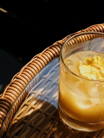 A sun-kissed cocktail on a wicker table. Sometimes the simplest drinks, enjoyed in the right light, are the most memorable.