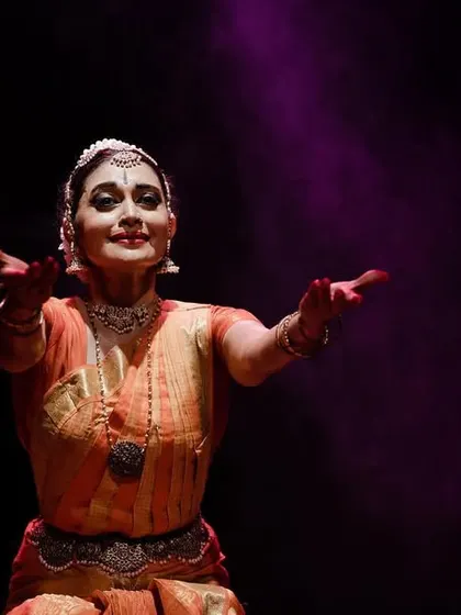 A welcoming and open expression, inviting the audience into the world of "SARVASYA."