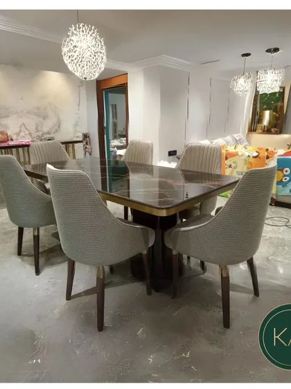 This dining set was created for a modern home, featuring a dark marble tabletop with subtle gold inlay. The accompanying chairs are upholstered in a textured grey fabric, offering a sleek and comfortable dining solution.