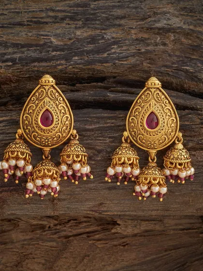 A beautiful pair of jhumkas with a teardrop-shaped stud and three small bells cascading below. Each bell is adorned with pearls and ruby-colored beads, creating a lovely cluster effect.