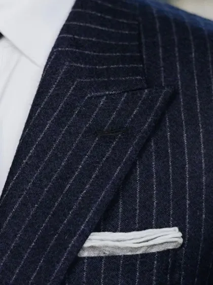 A detailed view of the lapel and pocket square on a custom pinstripe suit. It’s these small, perfected details that elevate a suit from standard to exceptional.