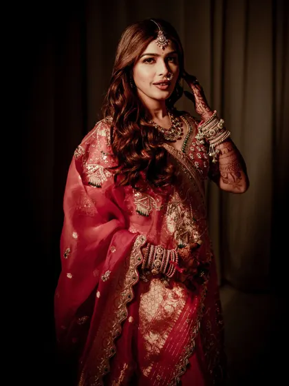 A classic pose highlighting the bride's soft smile and the intricate details of her henna. The makeup remains flawless, with a focus on enhancing her natural beauty.