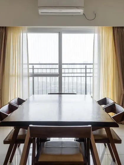 The dining area in our Prestige Tranquil project in Hyderabad, featuring a solid wood table and large windows that fill the space with natural light.