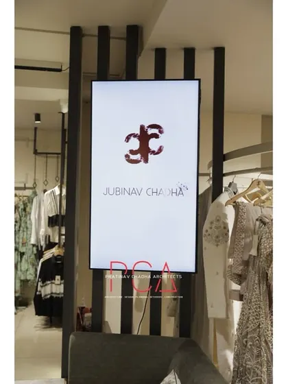 A digital display screen integrated into a slatted wall partition at the Jubinav Chadha studio, used for showcasing fashion collections.