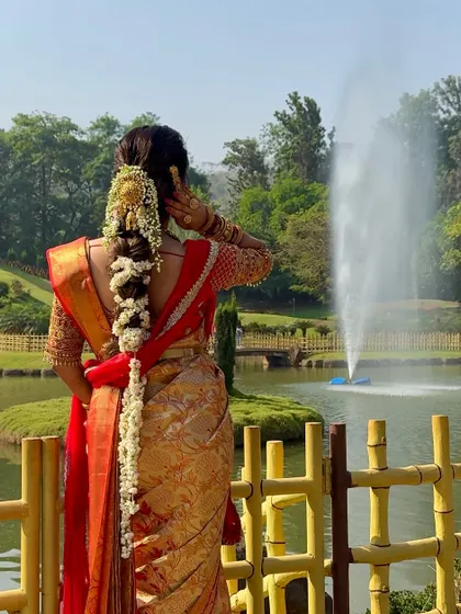 The back view of a South Indian bride, showcasing her elaborate floral braid and the elegant fall of her Kanchivaram saree.