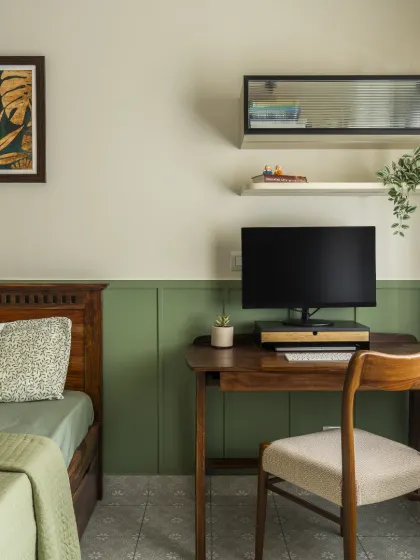Another view of the dark wood study unit, showing how it fits perfectly next to the bed. The design is complemented by botanical artwork, creating a calm and inspiring workspace.
