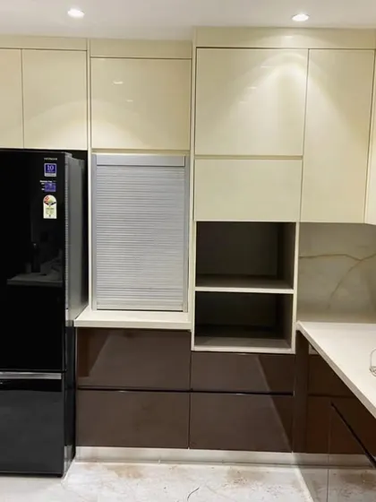 A close-up of the appliance section, featuring a black refrigerator, a rolling shutter for the appliance garage, and a mix of open and closed shelving for versatile storage.