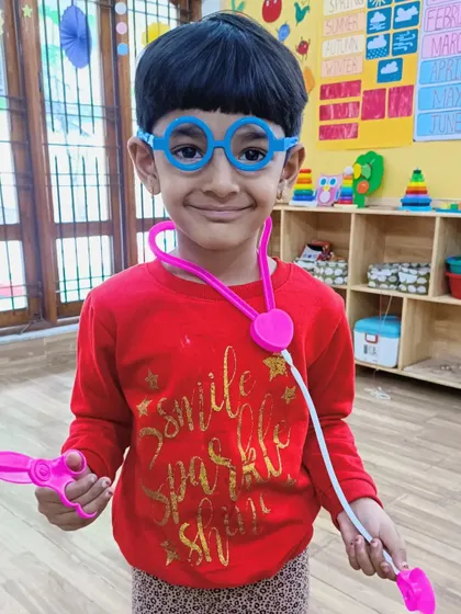 A smiling "doctor" with his toy stethoscope and scissors.