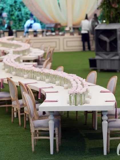 We designed this unique serpentine table for the family dining area. The centerpiece was a simple but elegant line of single pink roses in glass vases, running the entire length of the table.