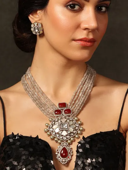 A unique piece featuring a large polki and mother-of-pearl pendant on a string of grey beads, accented with deep red stones.