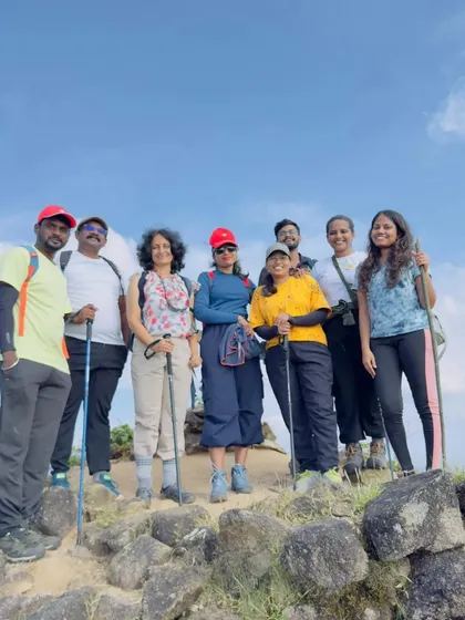 A group photo at the peak, with trekking poles and happy smiles.
