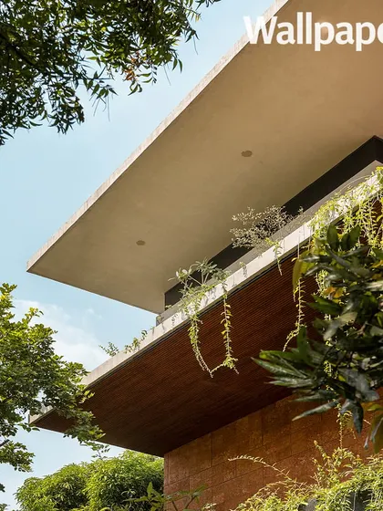 A low-angle shot from the Wallpaper* feature, emphasizing the dramatic cantilevered roof lines and lush greenery.