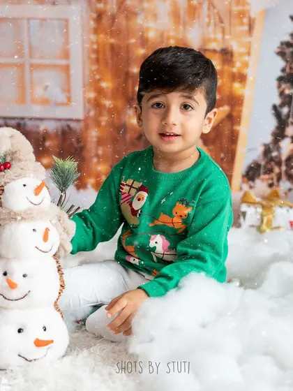A little boy in a cozy Christmas sweater, posing with his snowman friends. The snowy scene is one of my most popular holiday setups.
