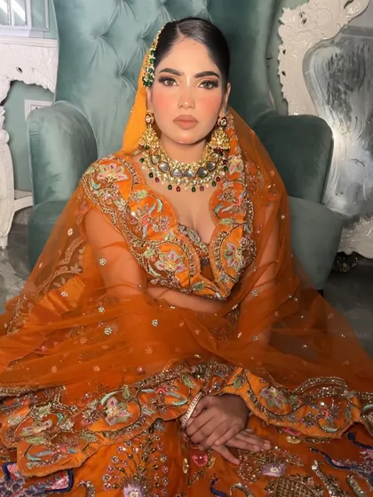 A close-up portrait that captures the warm, inviting feel of this autumn-inspired bridal look. The kundan jewellery with green and red accents adds a lovely contrast.