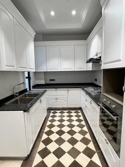 This is our take on a Victorian classical kitchen. It combines timeless design, like the checkerboard flooring and elegant white cabinetry, with modern functionality, including a fully equipped setup with a built-in hob and chimney.