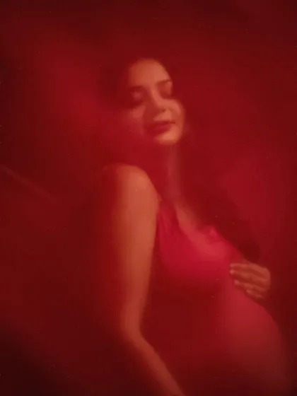 Bathed in crimson. This artistic, moody portrait uses a sheer red fabric to create a soft, dreamlike effect. It’s a poetic and emotional interpretation of the maternity journey.