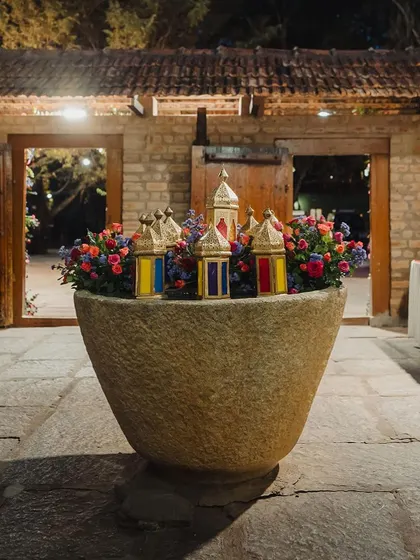 A large stone urli is filled with flowers and Moroccan lanterns, creating a stunning decor piece at the entrance of the venue.