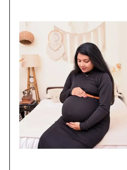 A quiet, reflective moment for the mom-to-be. Seated on the bed in our Boho-themed room, this portrait captures the gentle and personal side of the pregnancy journey. The black bodycon dress elegantly shows off her bump.