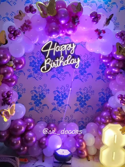 This magical fairy-themed 8th birthday decor uses a purple and pink balloon ring, accented with golden butterfly stickers and a large light-up number '8'.