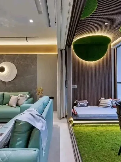 A view of a completed 2BHK interior, showing the living room connected to a beautifully designed balcony with artificial grass and a cozy seating nook.