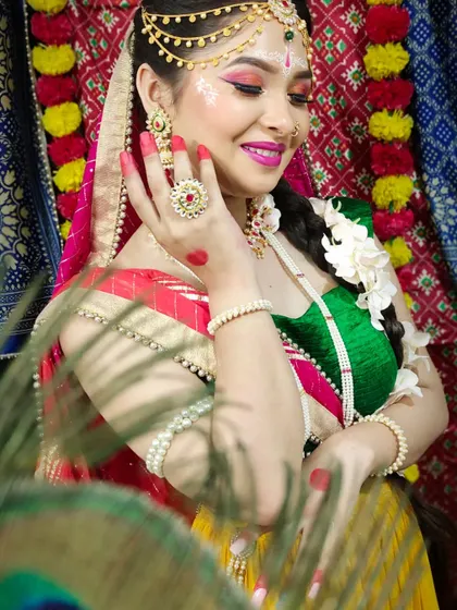 The Radha look from our Janmashtami shoot, featuring bright pink and orange eye makeup, floral jewelry, and a playful expression.