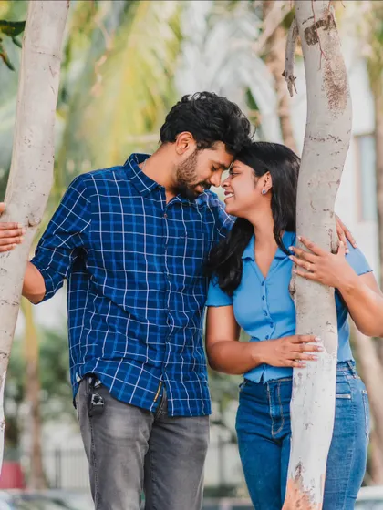 An intimate portrait of a couple framed by tree trunks, showcasing a quiet moment of connection during their casual pre-wedding shoot.