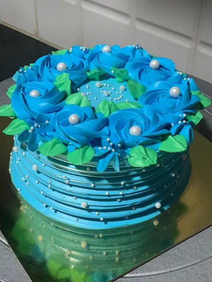 A striking blue floral cake. The vibrant blue roses are piped on top, and the sides have a delicate lined texture.
