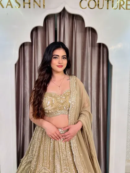 A close-up of a model wearing a sparkly golden lehenga. Her smile says it all. This outfit is designed to make you feel happy and confident.