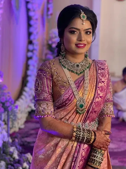 Another shot from her reception. The purple and pink tones of her saree are perfectly complemented by the green stones in her jewellery.