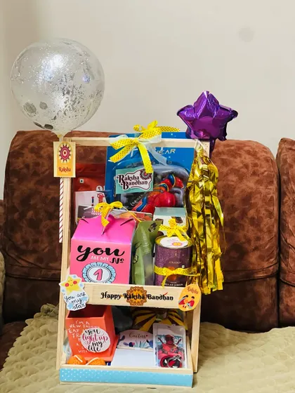 The full view of the festive two-tiered Rakhi hamper, complete with a confetti balloon and a star balloon.