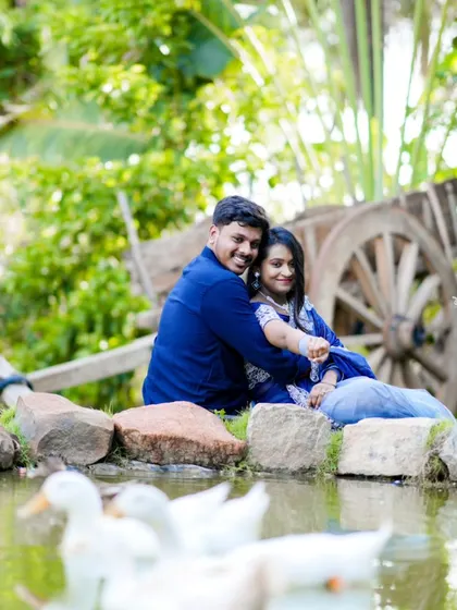 A serene pre-wedding photo by a pond with ducks. The natural setting and calm water create a peaceful and romantic mood.