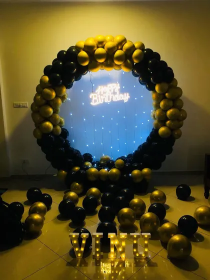 A simple yet stunning black and gold balloon ring decoration. This setup is great for smaller spaces, providing a beautiful photo backdrop with a neon sign and marquee letters without needing the full prop display.