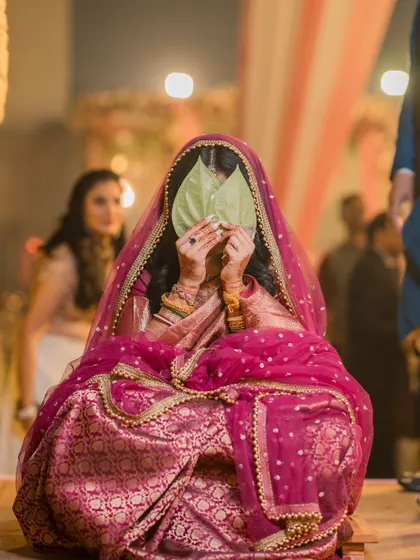 A traditional Bengali wedding moment where the bride hides her face behind betel leaves before the big reveal. A beautiful and culturally rich shot.