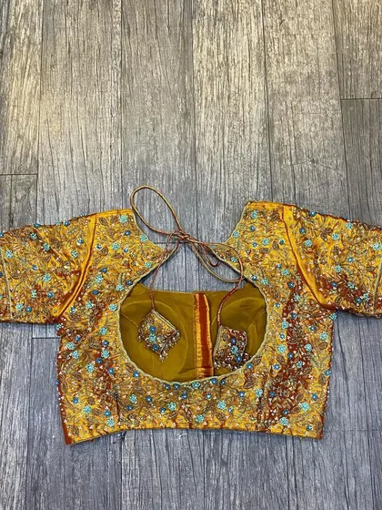 This is a heavily worked blouse with multi-color embroidery. The design is dense and intricate, perfect for pairing with a grand wedding saree.