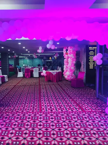 A balloon arch marks the entrance to this birthday party, creating a welcoming gateway for guests as they arrive. The pink lighting adds to the party mood.