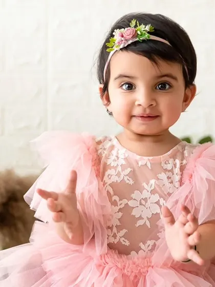A happy, interactive moment from a pink-themed sitter session, with the baby clapping her hands.