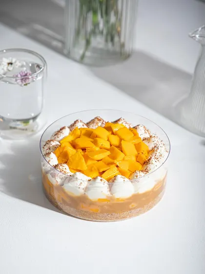 A close-up of our Mango Tres Leches, topped with fresh mango and a dusting of cocoa.