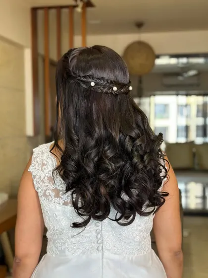 A romantic half-updo for a white wedding. I created a delicate braid crown and added small pearls for a touch of elegance, letting the rest of the hair flow in soft curls.