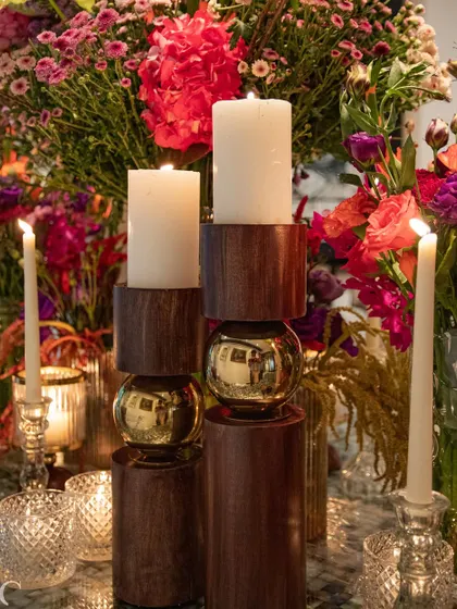 A close-up on the modern wooden and brass candle holders, which add a contemporary and masculine touch to the vibrant floral design. The contrast between the materials is visually striking.