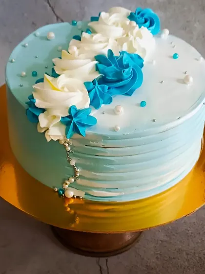 A simple and elegant cake with blue and white floral piping, perfect for any occasion.