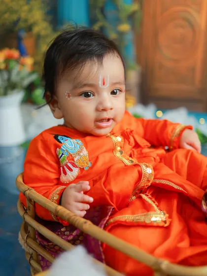 This little one looks so peaceful and content in his traditional orange attire. The embroidered fish detail adds a unique touch to the costume.
