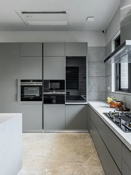 The kitchen's main wall includes integrated Siemens appliances and a sleek hob, all set against a backdrop of large-format tiles that mimic the look of concrete.