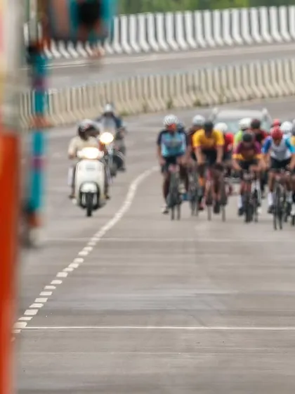 An elite rider leads the peloton past a large truck, a reminder of the dynamic and sometimes challenging environment of road racing.