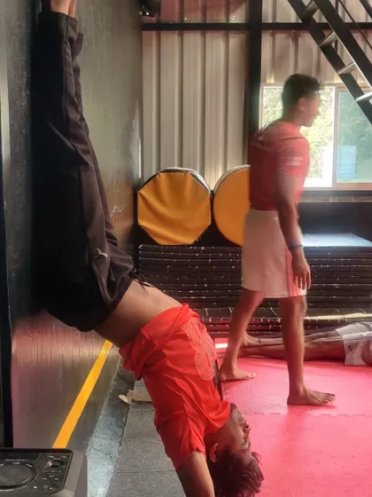 This student is working on a wall-assisted handstand, a fantastic exercise for building shoulder strength and core stability.