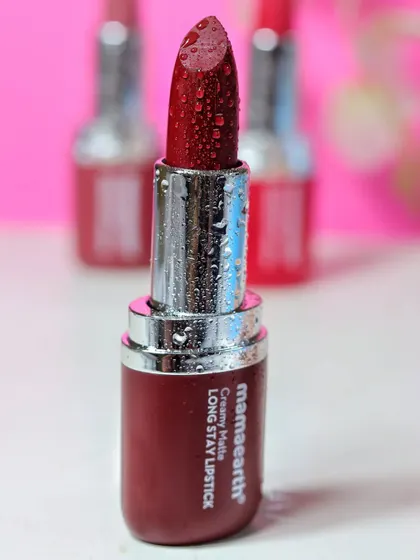 A focused shot on a single deep red Mamaearth lipstick, with other shades blurred in the background to create depth and highlight the hero product.