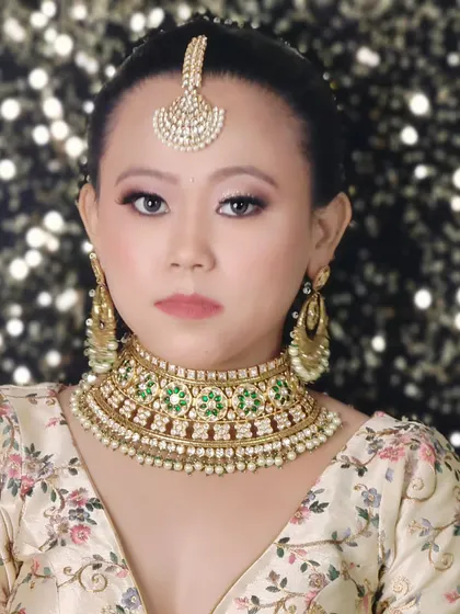 A simple and elegant look featuring a Polki choker with green stones and a matching maang tikka. This is a great choice for someone who prefers minimalist bridal jewellery.