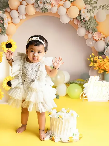 Another angle of this adorable sunflower-themed first birthday shoot. The balloon arch and floral details create a beautiful frame for this special milestone.