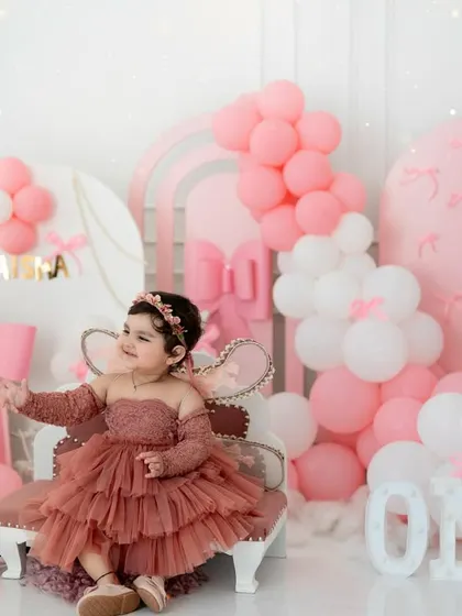 Pretty in pink for her first birthday. This elaborate setup with pink bows, balloons, and a princess chair creates a dreamy, fairytale photoshoot.