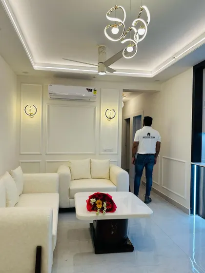 A full view of a bright and airy living room in a JM Florence project. The all-white theme, from the sofas to the wall molding, is accented by modern lighting, creating a clean and sophisticated look.